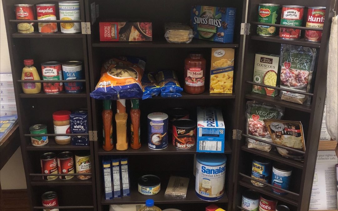 Pantry cupboard full of canned food with sign that says Little Free Pantry.