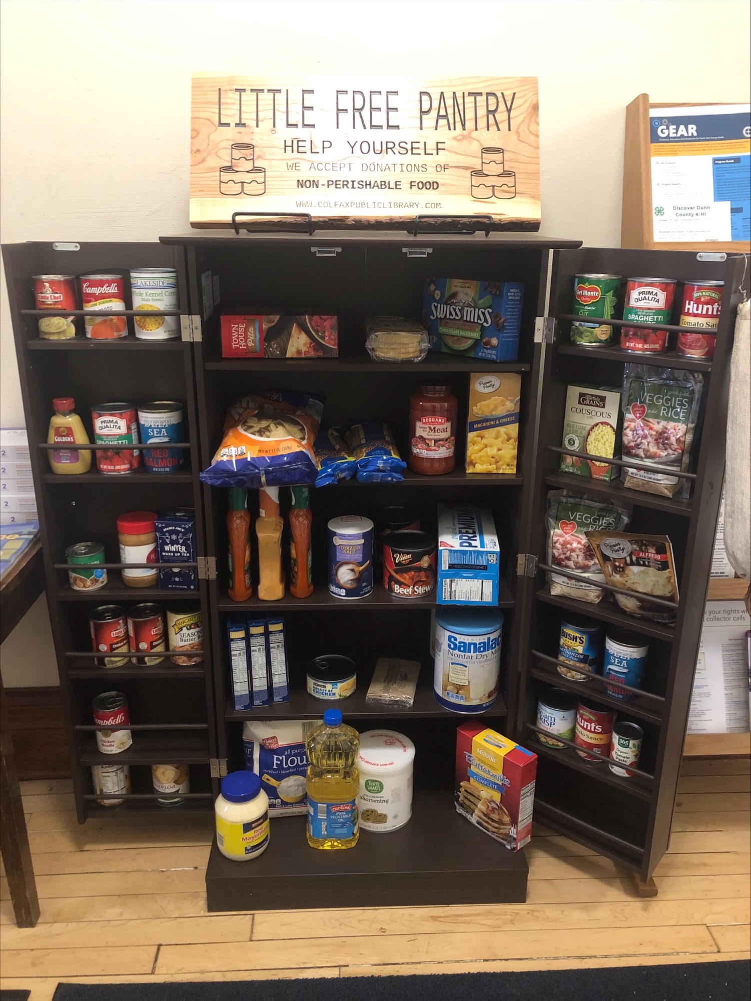 Pantry cupboard full of canned food with sign that says Little Free Pantry.